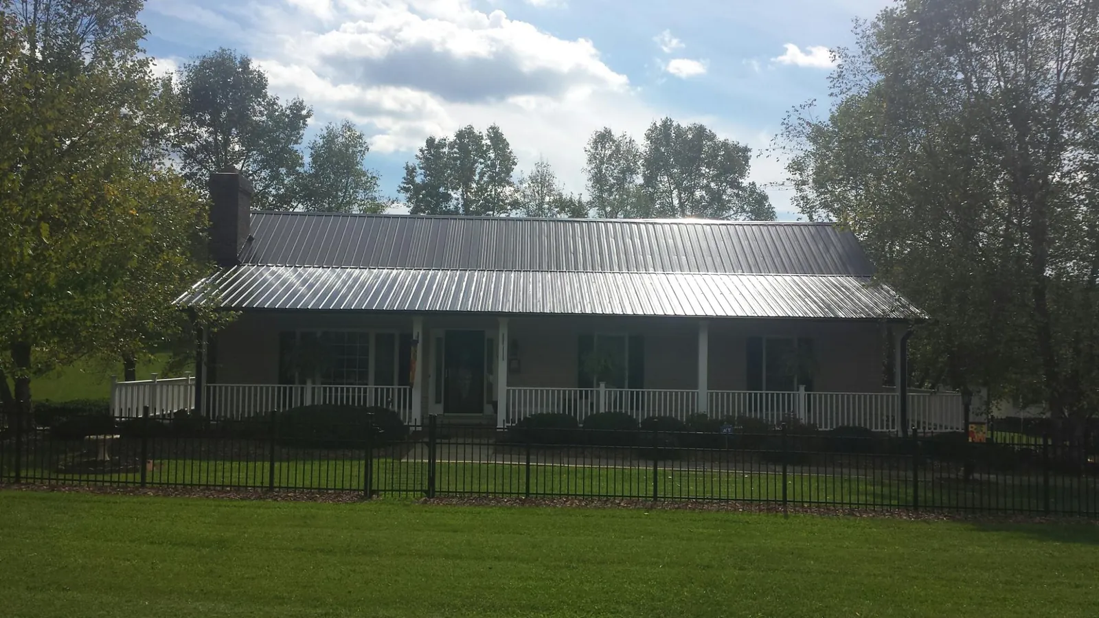 Gray metal roof on a brick ranch with a full width front porch — Gutter Guard Installation work by our crew in Valley Falls