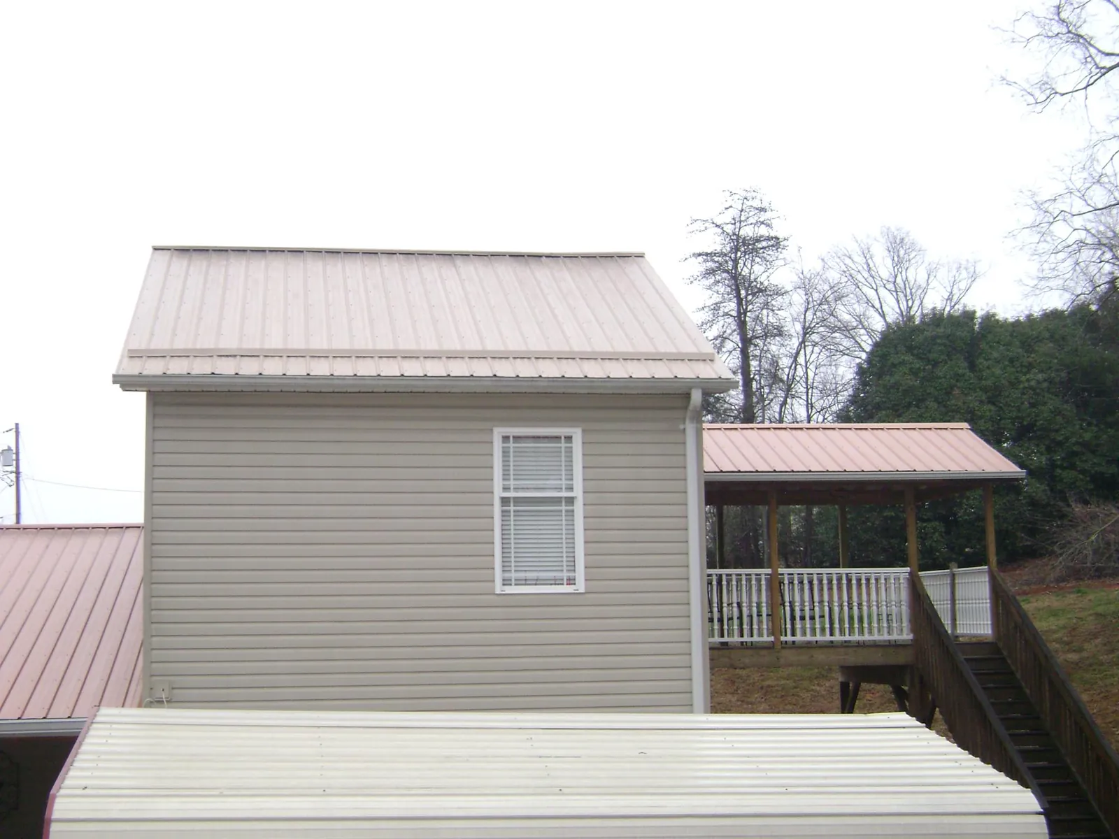 Tan metal roofs on a two story addition and attached porch, from a Roof Replacement job in Valley Falls